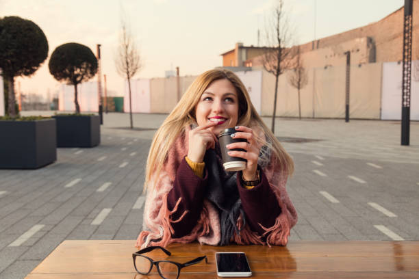 istock Attractive girl drinking coffee outdoors and using cellphone outdoors. 867688852