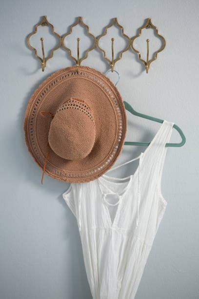 istock Hat and dress hanging against white wall 867689328