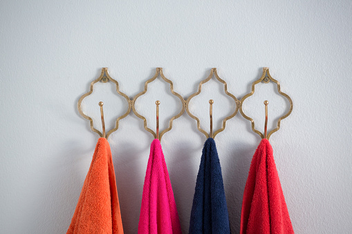 Colorful towels hanging on hook against white wall