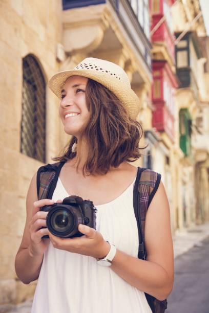 istock Young woman tourist with camera hat and backpack sightseeing in Valletta, Malta 867700200
