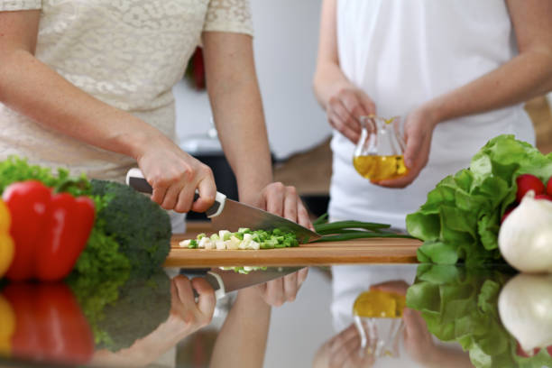 istock Close-up of  human hands  cooking in a kitchen. Friends having fun while preparing fresh salad. Vegetarian, healthy meal and friendship concept 867700252