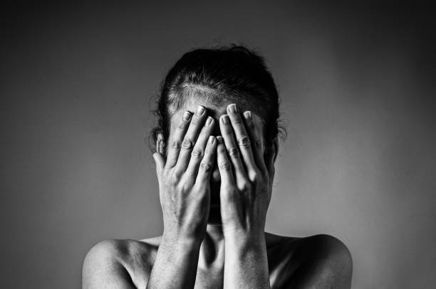 Concept of fear, shame, domestic violence. Concept of fear, shame, domestic violence. Woman covers her face her hands on light  scratched background. Black and white image. in bounds stock pictures, royalty-free photos & images