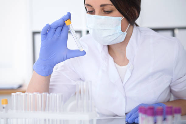 close-up of professional female scientist in protective eyeglasses making experiment with reagents in laboratory. medicine and research concept - close up medical test exam people imagens e fotografias de stock