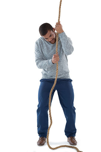 Young male executive pulling the rope against white background