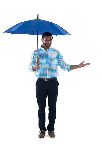 Male executive standing under umbrella against white background