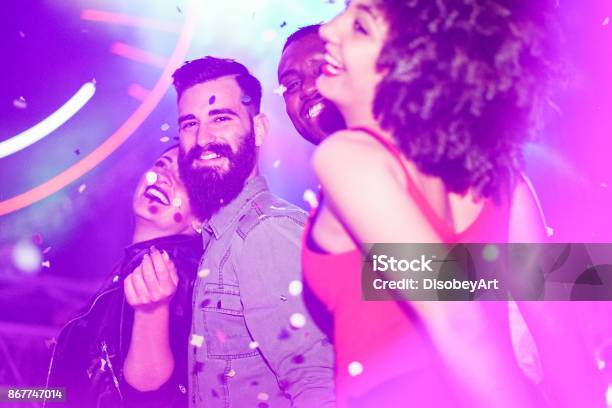 Happy Friends Having Fun In Night Club With Canon Ball Throwing Confetti Young People Enjoying Weekend Nightlife With Original Laser Lights Color Soft Focus On Bearded White Man Warm Filter Stock Photo - Download Image Now