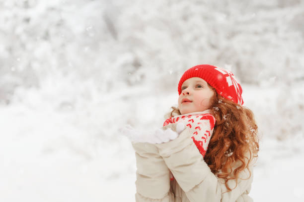 istock Curly hair girl catching falling snowflakes. 867747304