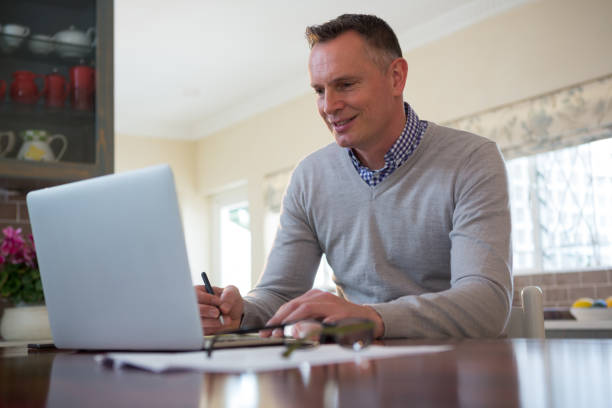 istock Man using laptop in living room 867753872
