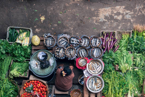 The trade place of the seller of the fish and vegetables on the Ubud market Bali: Balinese woman selling the fish and the vegetables on the main market of Ubud, top view balinese culture stock pictures, royalty-free photos & images