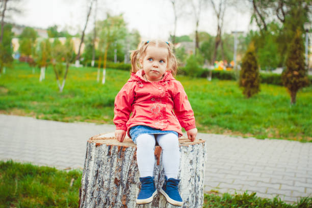 istock girl sitting on a stump 867754170