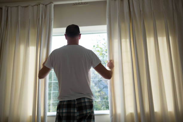 istock Man opening window curtain in bedroom 867761084