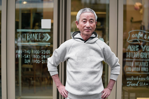 Happy young man wearing casual clothes smiling and looking at camera against silver wall.