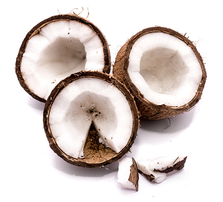 Three coconut halves and meat pieces isolated on white background