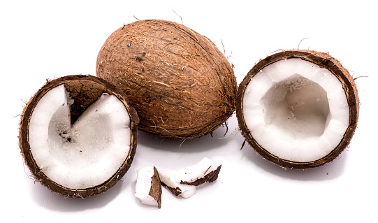 One whole coconut, two halves and meat pieces isolated on white background