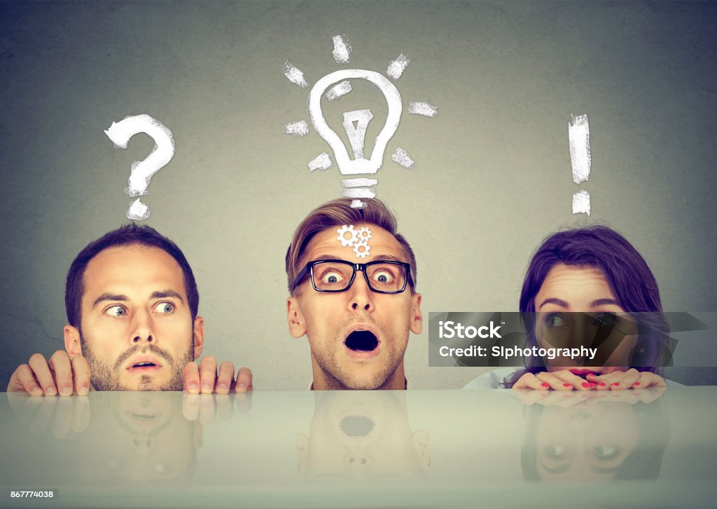 Scared anxious young people two men and a woman hiding peeking form under the table having questions and ideas to solve problem Question Mark Stock Photo