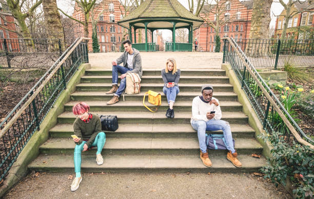 istock Group of multiracial friends using mobile smart phone sitting on stairs at park - Young hipster people addicted by smartphone on social network community - Technology concept - Desaturated color tones 867775876