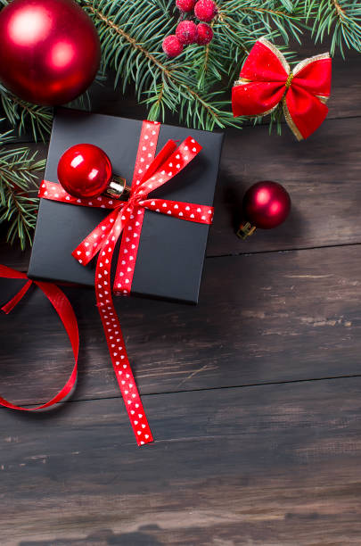 istock Black christmas  gift  box with red ribbon and fir branches 867785068