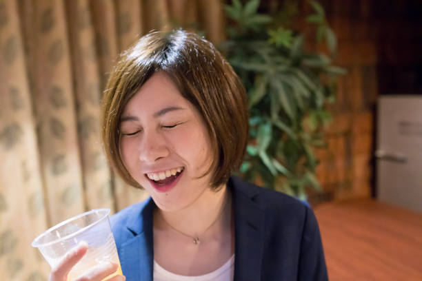 仕事の後 cocktal を飲んでいる若いビジネス女性 - アルコール 顔つき ストックフォトと画像