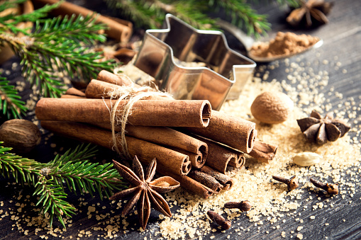 Christmas spices and baking ingredients on dark wooden background. Cinnamon, anise stars, nutmeg, cardamom, cloves, brown sugar and cocoa powder for Christmas cake, cookies.