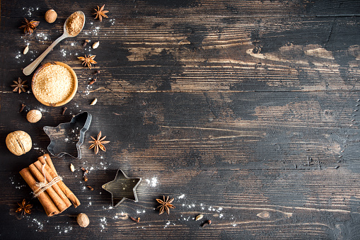 Christmas spices and baking ingredients on wooden background. Cinnamon, anise stars, nutmeg, cardamom, cloves, brown sugar and cocoa powder for Christmas cake, cookies.
