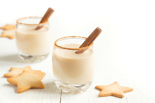 Eggnog with cinnamon and nutmeg for Christmas and winter holidays. Christmas Eggnog, gingerbread cookies isolated on white background.