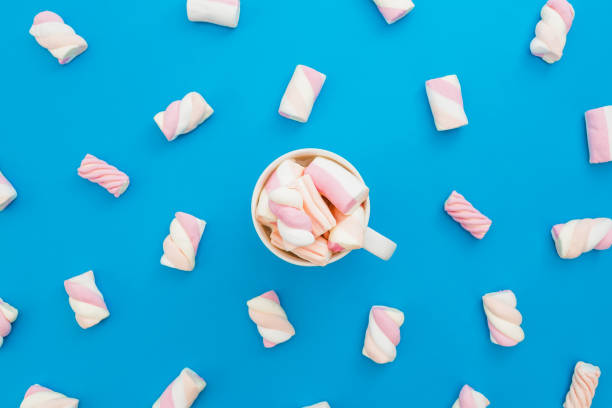 istock Cappuccino mug with sugary marshmallows on blue background. Flat lay, top view 867802476