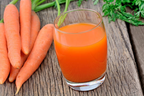 istock Carrot juice in a glass on wooden table 867820532