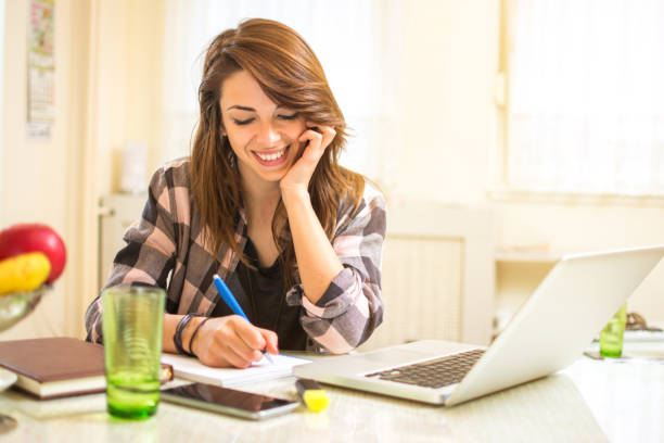 istock Smiling university student studying with books and laptop at home. 867826996