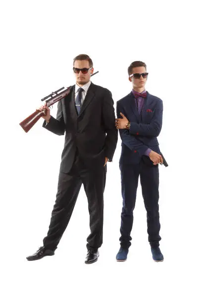 Two men in fancy suits and ties armed with guns.