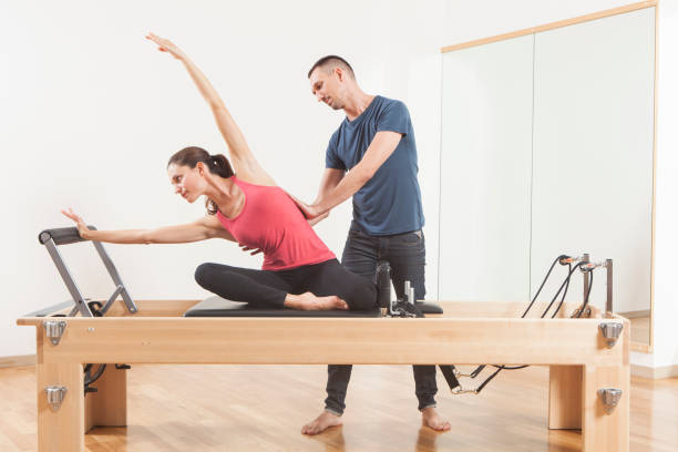 aula de pilates no reformador, pessoal treinador jovem bonita - stretching yoga men good posture - fotografias e filmes do acervo