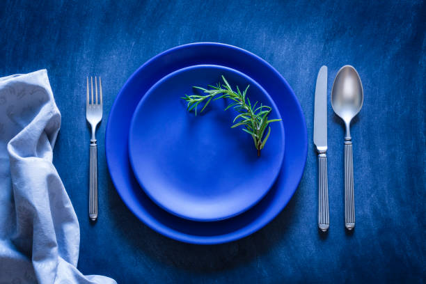 ajuste de lugar entonada azul tiro desde arriba sobre fondo oscuro - silverware place setting napkin fork fotografías e imágenes de stock