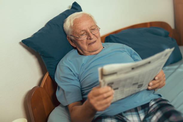 istock Senior man in glasses reading newspaper at home 867845794