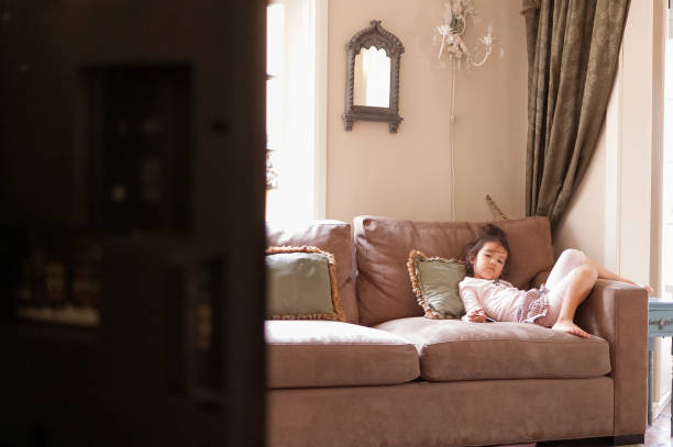 istock Bored little girl watching TV on couch 867856122