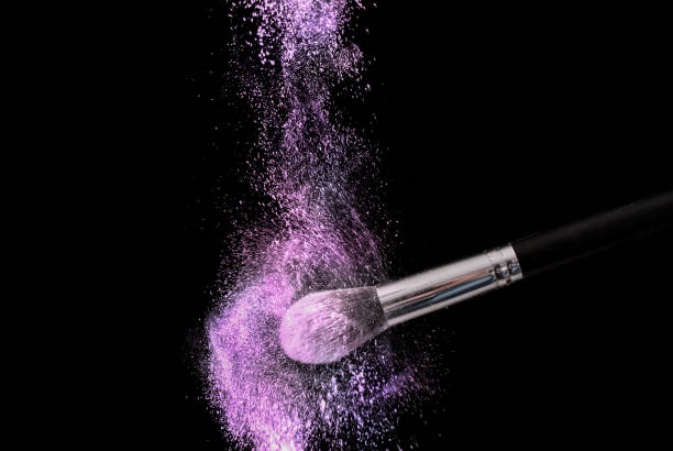 poeira de explosão de pó de roxo e compõem a escova em fundo preto - face powder exploding make up dust - fotografias e filmes do acervo