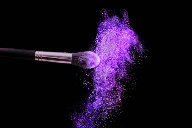 istock Make up brush and powder explosion in purple color isolated on black 867872764