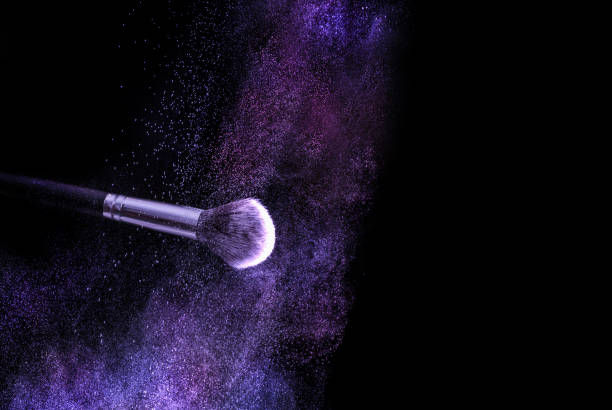 Make up brush and colorful powder explosion dust cloud on black background