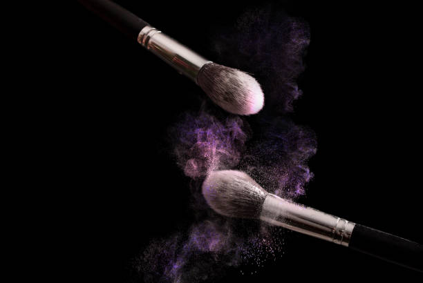 compõem a escova e o pó cor roxo explosão isolada no fundo preto - face powder exploding make up dust - fotografias e filmes do acervo