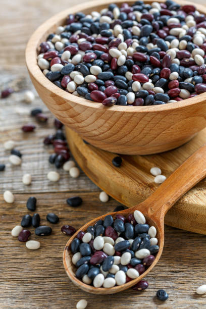 istock Wooden bowl and spoon with red, white, black beans. 867879480