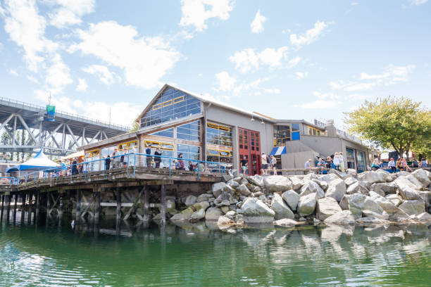 Granville Island Public Market Visitors resting at the Granville Island Public Market in Vancouver, Canada. It's home to over 100 vendors offering fresh seafood, meats, and specialty foods. Granville Island is located across False Creek from downtown Vancouver. granville island stock pictures, royalty-free photos & images