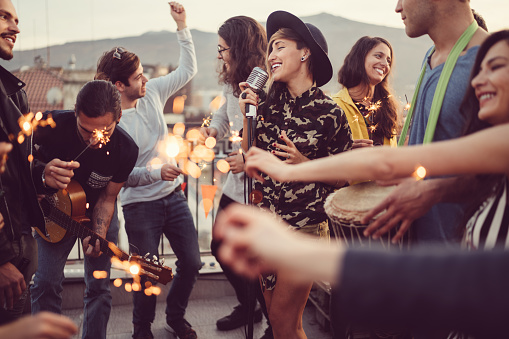 Group of friends with sparklers enjoying a guitar party for Christmas on the rooftop