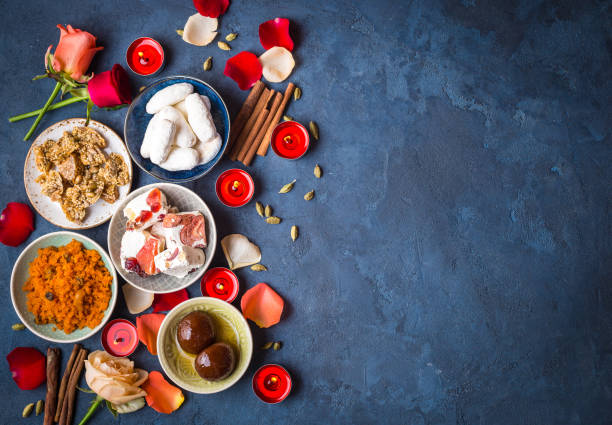 Indian Diwali sweets Indian Diwali celebratory background with traditional sweets. Gulab jamun, carrot halwa, snacks with candles, flowers. Assorted indian desserts. Holiday festive table. Diwali setting. Space for text india sweets stock pictures, royalty-free photos & images