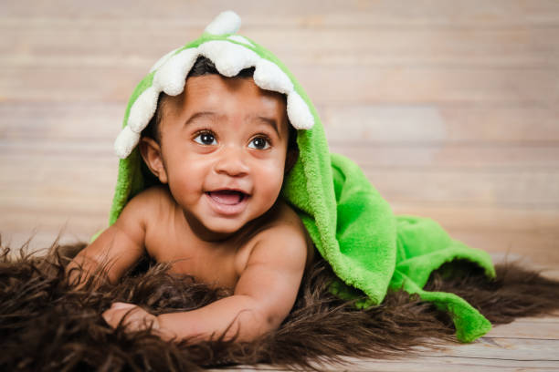 Infant dogla boy wearing bath robe laying on tummy belly Infant dogla boy wearing bath robe laying on his tummy belly fluffy furry throw wooden background modern studio shoot modern look biracial newborn stock pictures, royalty-free photos & images