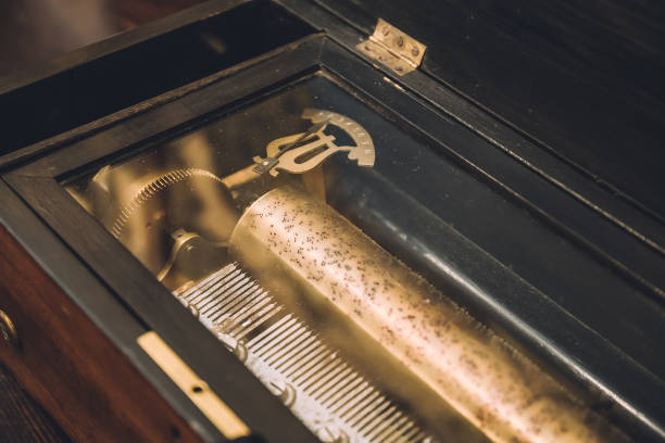 A close-up view of a wooden retro pinball game with metal pegs and numbered slots, illuminated by warm, moody lighting. Hands are seen interacting with the game, creating a nostalgic and tactile moment.