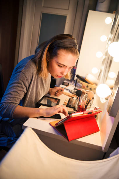 istock Young woman looking at a makeup tutorial on social media at home 867925076