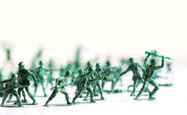 molti soldatini giocattolo di plastica dell'esercito verde organizzati su una superficie bianca e uno sfondo, isolati, con soldati di plastica fuori fuoco sullo sfondo - bambola giocattolo foto e immagini stock