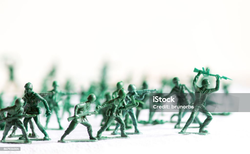 Many green army plastic toy soldiers organized on top of a white surface and background, isolated, with out of focus plastic soldiers in the background Green plastic soldiers, organized, white background isolated Army Stock Photo