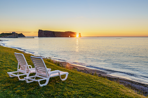 Percé Rock at sunrsie with white chairs in the foreground