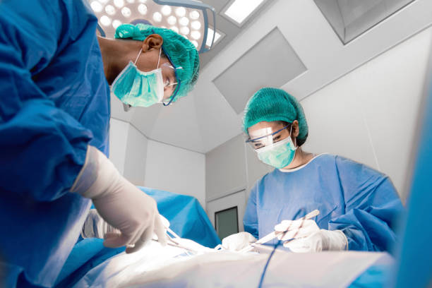 Doctors and nurse with tools in hands making surgery in operation room. Health care and Hospital concept stock photo