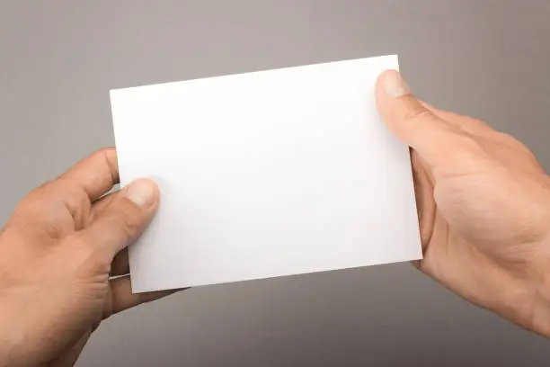 Blank postcard in hands on a gray background. Leaflet A6 mockup