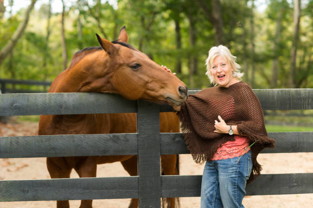 istock Blond woman laughs at horse biting poncho 867994516